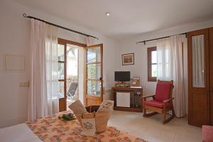 a living room with a chair and a desk and windows at Agroturisme Na Martina in Portopetro
