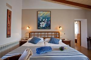 a bedroom with a bed with blue pillows and a painting at Agroturisme Na Martina in Portopetro