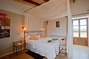 a bedroom with a white bed with a canopy at Agroturisme Na Martina in Portopetro