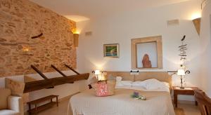 a bedroom with a bed and a stone wall at Agroturisme Na Martina in Portopetro