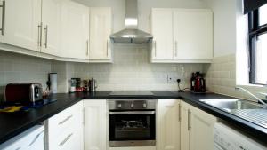 a kitchen with white cabinets and a sink and a stove at Liberty Townhouses in Dublin