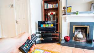 a person holding a remote control in a living room with a fireplace at Liberty Townhouses in Dublin