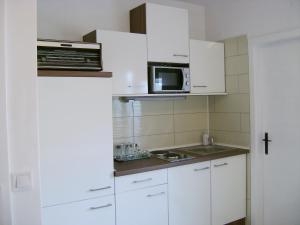 eine kleine Küche mit weißen Schränken und einer Mikrowelle in der Unterkunft Apartment Veronica in Split