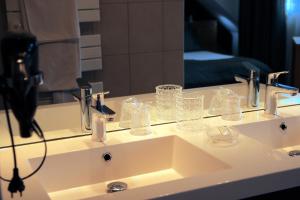 a bathroom sink with glasses and a mirror at ART Hôtel in Kaysersberg
