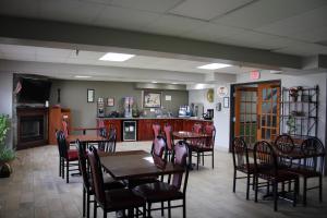 a dining room with tables and chairs and a kitchen at Super 8 by Wyndham Shepherdsville - Louisville South I65 in Shepherdsville