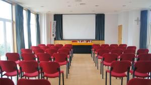 a conference room with red chairs and a screen at Kolping House in Lamego