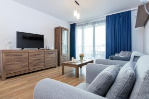 un soggiorno con 2 sedie blu e una TV a schermo piatto di Apartament Wawrzyńca a Cracovia