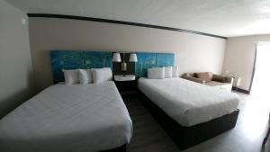 a hotel room with two beds and a chair at Garden City Inn in Myrtle Beach