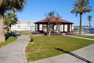 a park with a building and palm trees and a walkway at Taymar in Chiclana de la Frontera