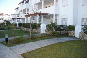a white building with a garden in front of it at Taymar in Chiclana de la Frontera