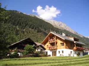 une maison dans un champ avec des montagnes en arrière-plan dans l'établissement Müllerhof, à Anterselva di Mezzo