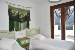 a bedroom with two beds and a painting on the wall at Apartamentos Vista Veleta in Capileira