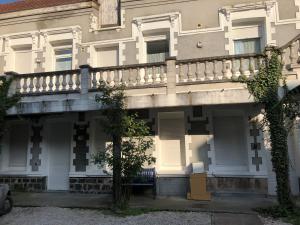a white building with a balcony on top of it at Aux Thermes, studio calme et paisible in Saint-Amand-les-Eaux