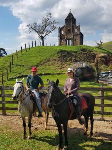 two people riding horses in front of a castle at Refúgio Horse in Santo Antônio do Pinhal