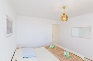 a white room with a bed and a chandelier at Rooms Nikola in Dubrovnik