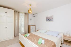 a white bedroom with a bed and a dresser at Rooms Nikola in Dubrovnik