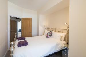 um quarto com uma cama com lençóis brancos e almofadas roxas em Kingsway Apartment em Bishop Auckland