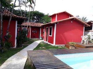 una casa roja con una piscina frente a ella en Pousada Maria da Toca, en Rio das Ostras