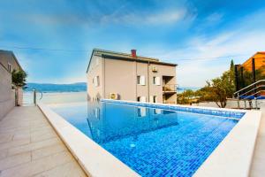 a swimming pool in front of a house with a building at Villa Amica in Trogir