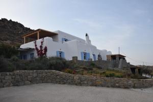 Andromeda Mykonos Villas & Suites في كالو ليفادي: منزل على تلة بجدار حجري