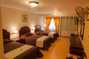 Habitación de hotel con 3 camas y ventilador. en Hotel Britania San Borja, en Lima