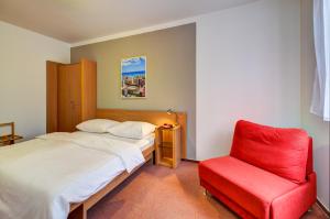 a bedroom with a bed and a red chair at Hotel Iberia in Opava