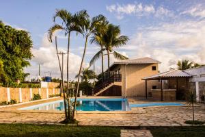 a house with a swimming pool and palm trees at Vilas Florence in Lauro de Freitas