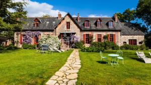 une grande maison en pierre avec des chaises et une table dans la cour dans l'établissement Le Petit Manoir de Kériolet, à Concarneau