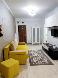 a living room with a yellow couch and a tv at Sarah Apartment in Constanţa