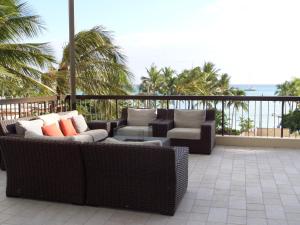 a patio with wicker furniture and chairs on a balcony at Waikiki Beach Tower in Honolulu