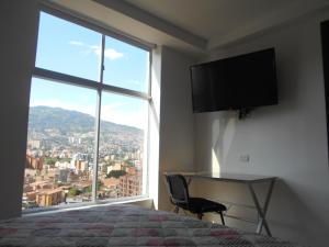 a bedroom with a bed and a desk and a large window at Apartasuites AV in Medellín
