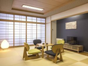 a living room with a table and chairs and a tv at Dogo-no-Yado Katsuragi in Matsuyama +3 photos