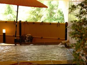 a pool of water with an umbrella in a building at Dogo-no-Yado Katsuragi in Matsuyama