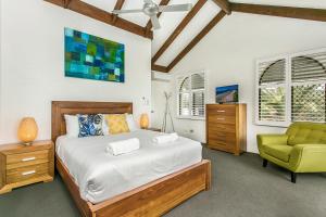 a bedroom with a bed and a green chair at The Terraces Main Beach in Byron Bay