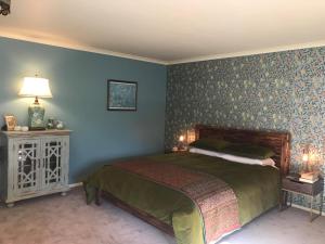 a bedroom with a bed and a blue wall at Glascroft Gardens - Bed & Breakfast in Patea