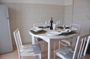 einen weißen Tisch mit weißen Stühlen und eine Flasche Wein in der Unterkunft la Moretta in Marina di Ragusa