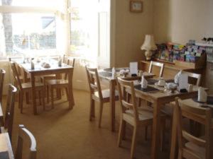 a dining room with tables and chairs and a window at Penmorvah in Penzance
