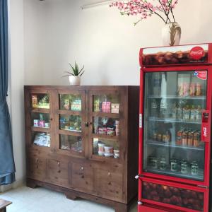 a coca cola refrigerator next to a wooden cabinet at Thao Trang Hotel in Dong Hoi