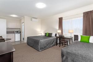 a hotel room with two beds and a kitchen at Redcliffe Motor Inn in Redcliffe