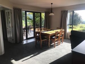 a dining room with a table and chairs and windows at Alpaca Farmstay in Dunedin