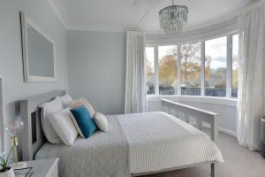 a white bedroom with a bed and a large window at River Retreat in Gore