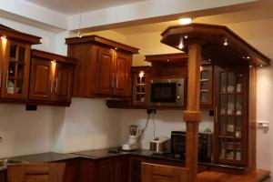 a kitchen with wooden cabinets and a microwave at Villa Royce in Kandy +28 photos
