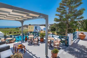 a patio with tables and chairs and a tree at Kalimera Hotel in Akrotiri