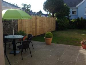 un patio con una mesa y una sombrilla verde en Lockinbar Holiday Apartments, en Tenby