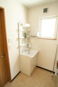 baño blanco con lavabo y ventana en Guest House COCO, en Lago Toya