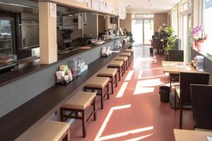 a restaurant with a long counter with tables and chairs at Guest House COCO in Lake Toya