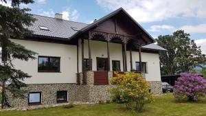 una casa blanca con techo negro en Apartmány Vízmberk en Velké Losiny