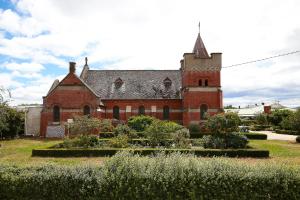 un ancien bâtiment en briques rouges avec une tour d'horloge dans l'établissement A Tassie Church, à Kempton