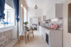 a kitchen with white cabinets and a table with chairs at La Piazza Apartment in Dubrovnik