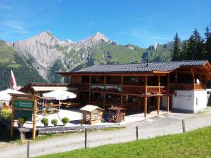 ein großes Holzgebäude mit Bergen im Hintergrund in der Unterkunft Ferienwohnung Kuenzer Alm in Matrei in Osttirol
